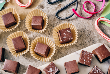 Easy Microwave Fudge cut into neat squares and placed in small paper cups with scissors and ribbon in the shot.