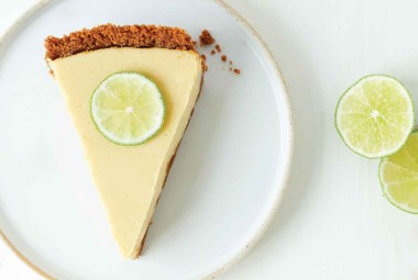 A slice of Classic Key Lime Pie with a graham cracker crust and sliced lime on top